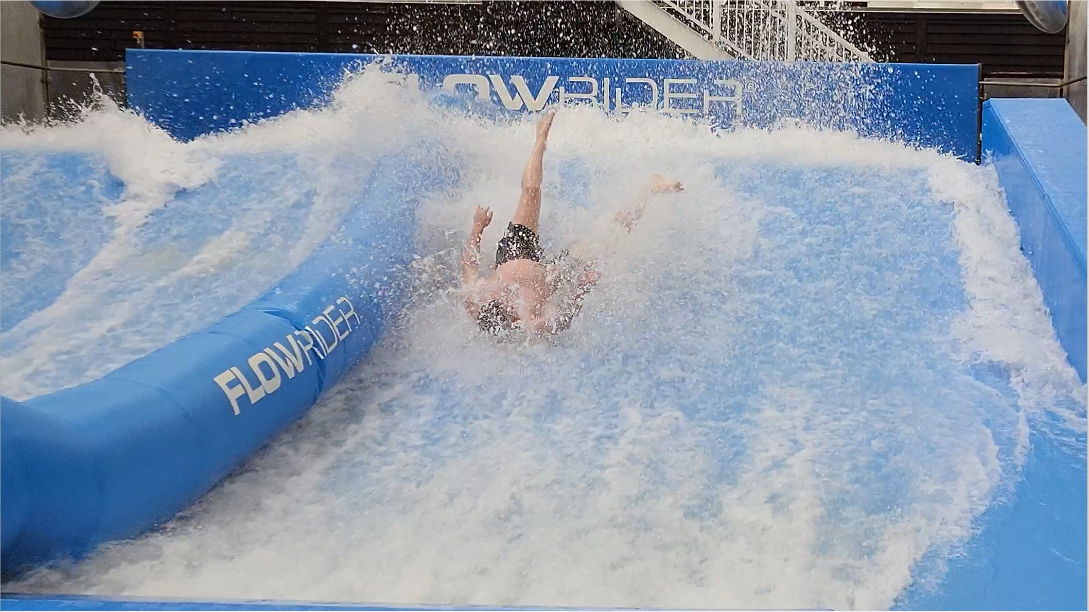 Brian Kinash upside down feet in the air from wiping out on the Flowrider surf simulator